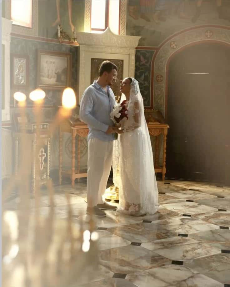 A bride and groom facing one another in a sunlit nave