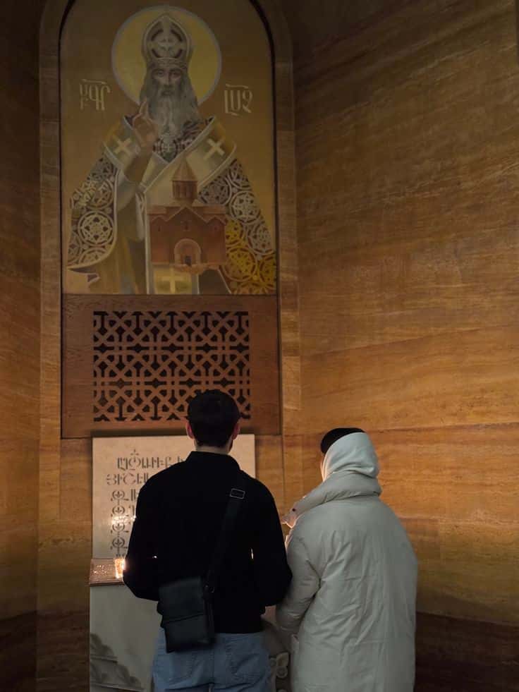 A couple lighting a candle before an icon