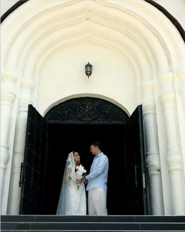 A bride and groom in the open doors of a church