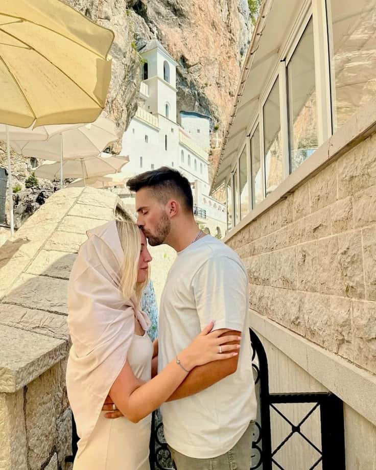 A couple on the steps below a monastery built into a cliff