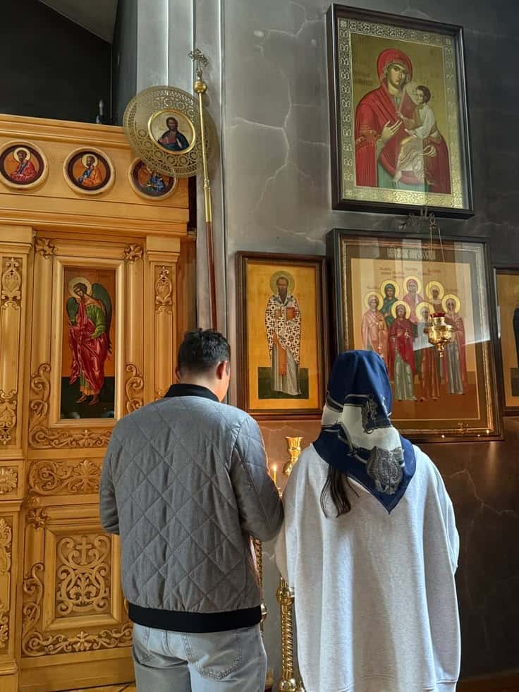 A couple standing quietly before the icons of a church