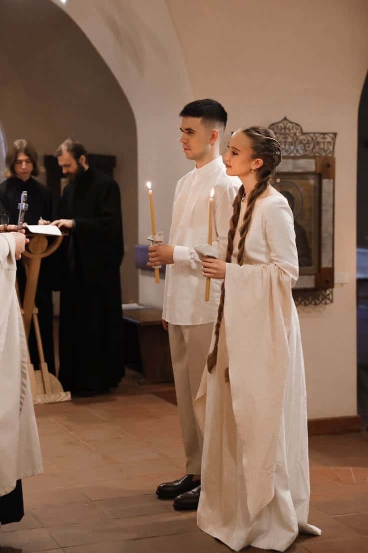 A bride and groom holding candles during an Orthodox wedding service
